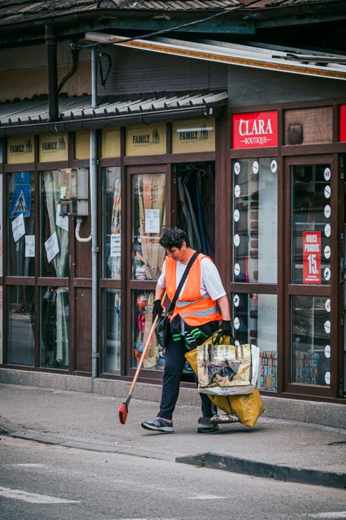 Free A street cleaner in an orange vest sweeps outside a boutique. Stock Photo