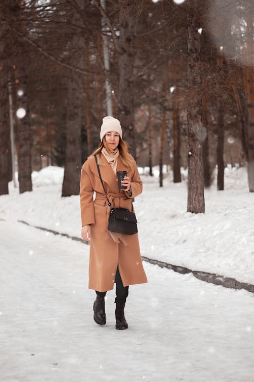 Free Woman in Brown Coat Standing on Snow Covered Ground Stock Photo