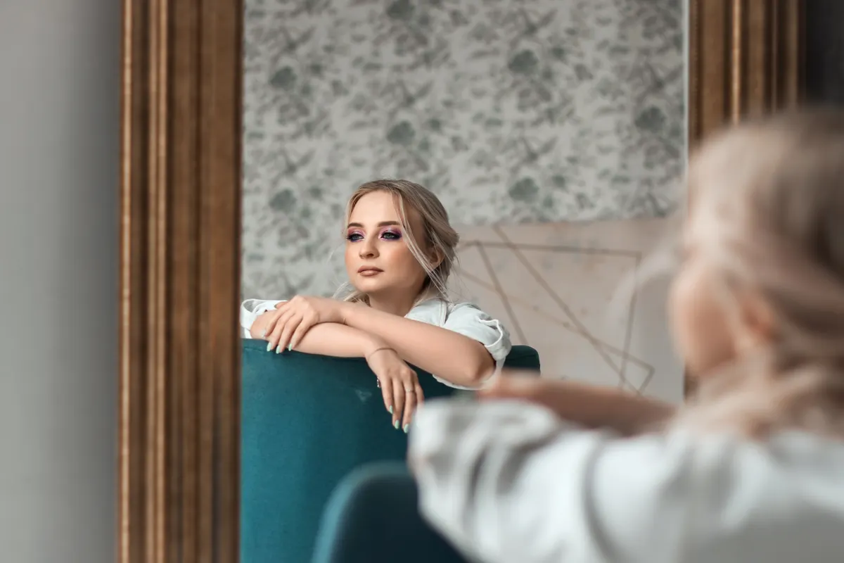 Frau betrachtet ihr Gesicht nach einer Microneedling Erfahrung im Spiegel.
