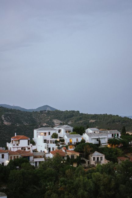 Scenic aerial shot of a traditional Greek village nestled among lush greenery and hills.