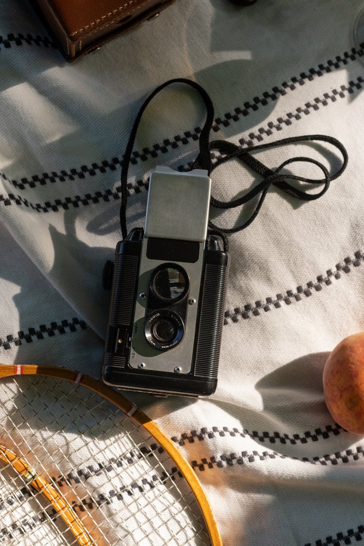 Black And Silver Camera On White Textile