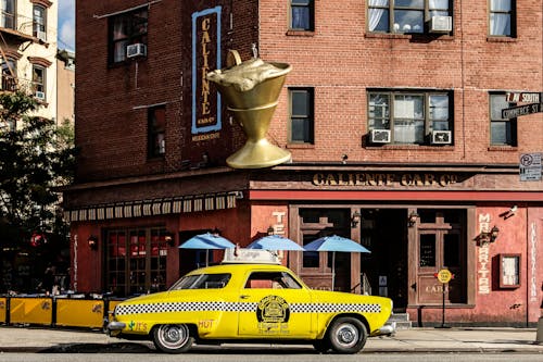 Free Yellow Taxi Cab in Front of Brown Building Stock Photo