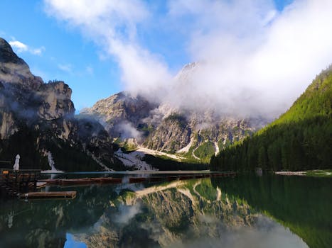 Serene reflection of the Dolomites at Lago di Braies, Italy, surrounded by lush green forests.