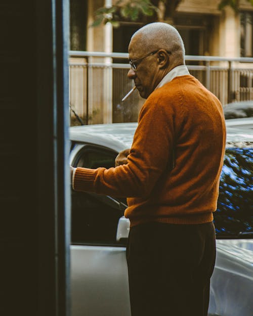 Free Elderly Man in Brown Sweater Smoking a Cigarette Stock Photo
