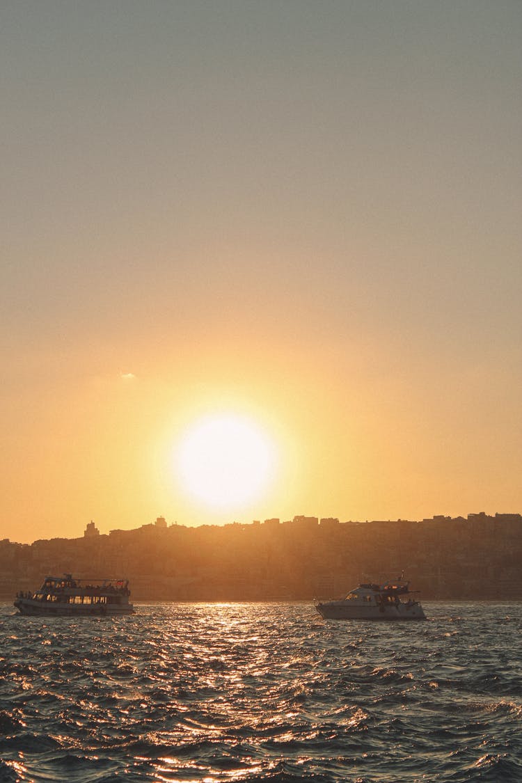 Photo Of A Glowing Sun With Boats On Sea 