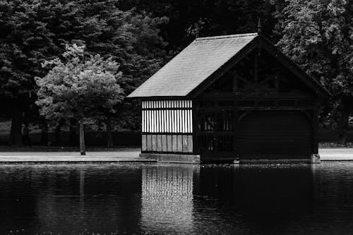 Grayscale Photo of a Cabin Near Body of Water