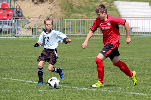 Two young soccer players engage in a competitive match on a sunny day outdoors.
