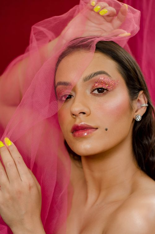 Free Close-up portrait of a woman with glitter makeup and pink veil, showcasing elegance and style. Stock Photo