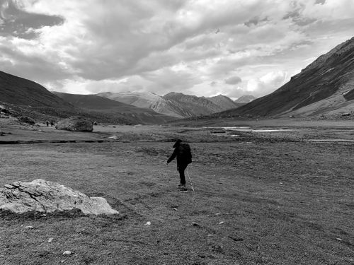 Free Silhouette of a backpacker hiking in a mountainous terrain with dramatic clouds. Stock Photo