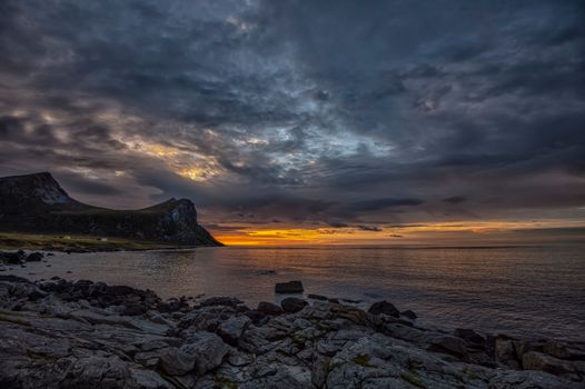Captivating sunset over Myrland coastline, highlighting dramatic clouds and rocky shore.