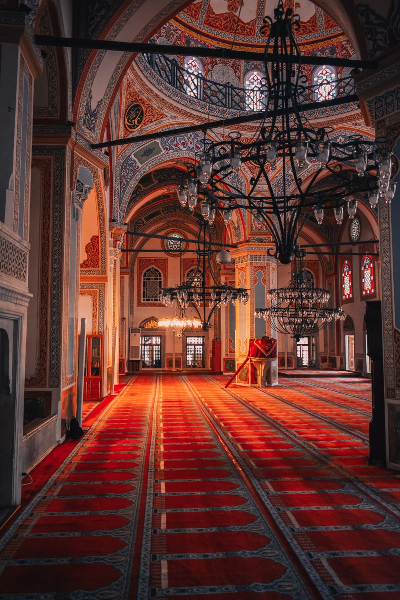 A beautifully ornate mosque interior showcasing chandeliers and vibrant red carpets
