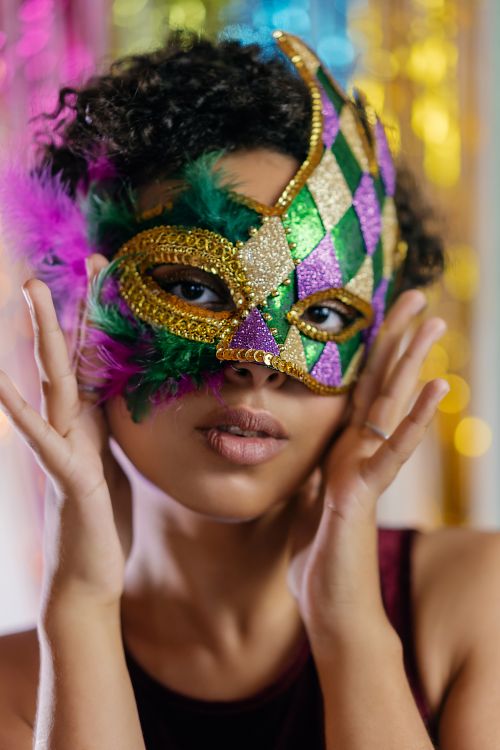 Free Stunning portrait of a young woman wearing a colorful Mardi Gras mask, perfect for celebration themes. Stock Photo