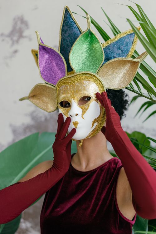 Free A woman wearing a vibrant and ornate masquerade mask styled with colorful petals. Stock Photo