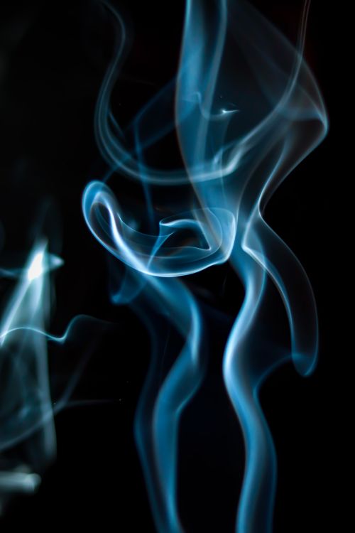 Free Captivating swirls of blue smoke set against a stark black background, creating a mysterious atmosphere. Stock Photo