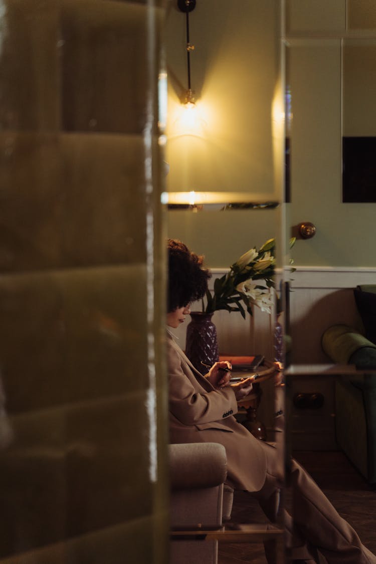 Woman Sitting On An Armchair Checking Her Phone