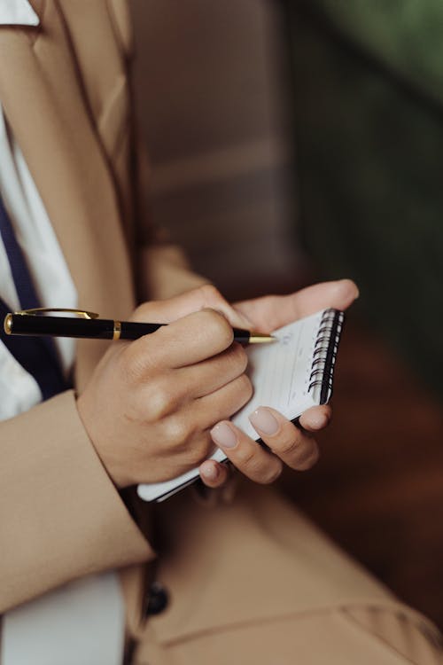 Free Close Up Photo of a Person Writing on a Notepad Stock Photo