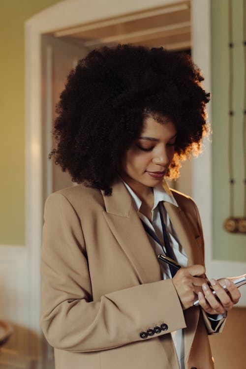 Taking Notes of a Woman Standing Wearing a Blazer · Free Stock Photo