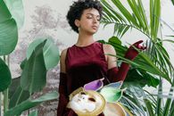Woman in Purple Sleeveless Dress Holding Coconut Fruit
