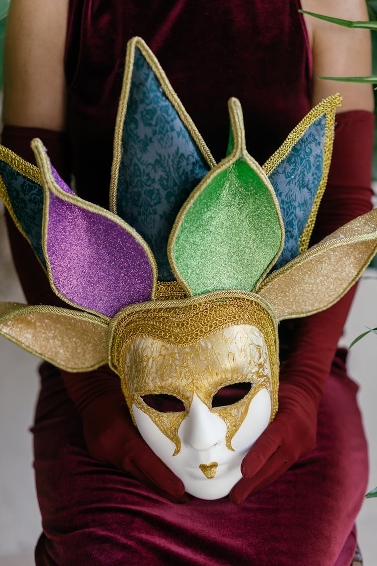 Person In Maroon Velvet Dress Holding A Mask