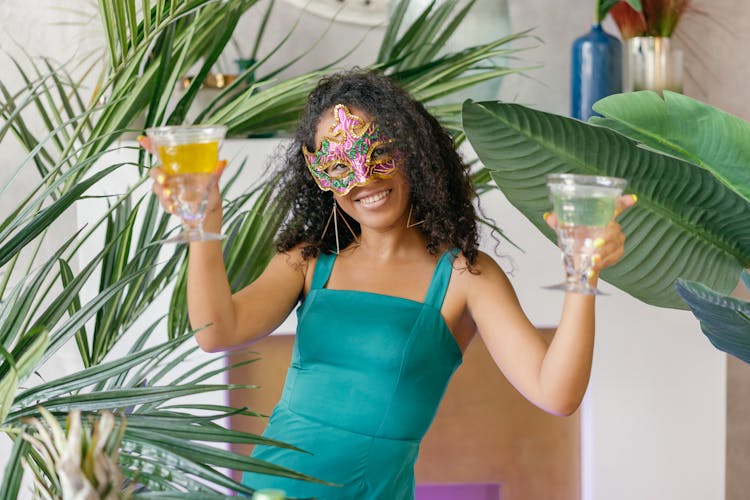 Woman On Mardi Gras Mask Holding Two Glasses Of Drinks