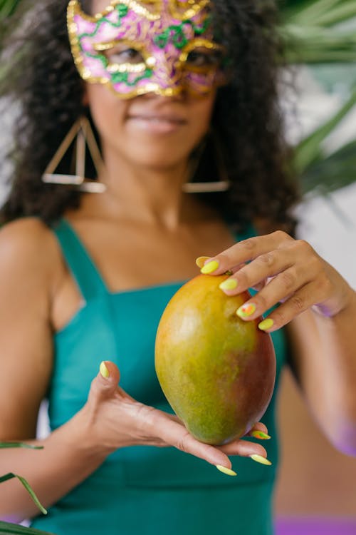 Woman Wearing Mask Holding a Mango