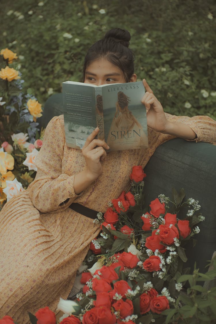 Woman Sitting On A Bench Covering Her Face With A Book