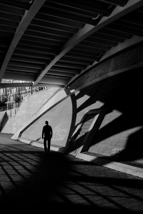 Free Moody black and white silhouette of a person walking under a bridge in Berlin, Germany. Stock Photo