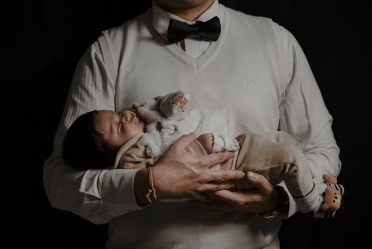 Midsection Of A Man Holding A Sleeping Baby