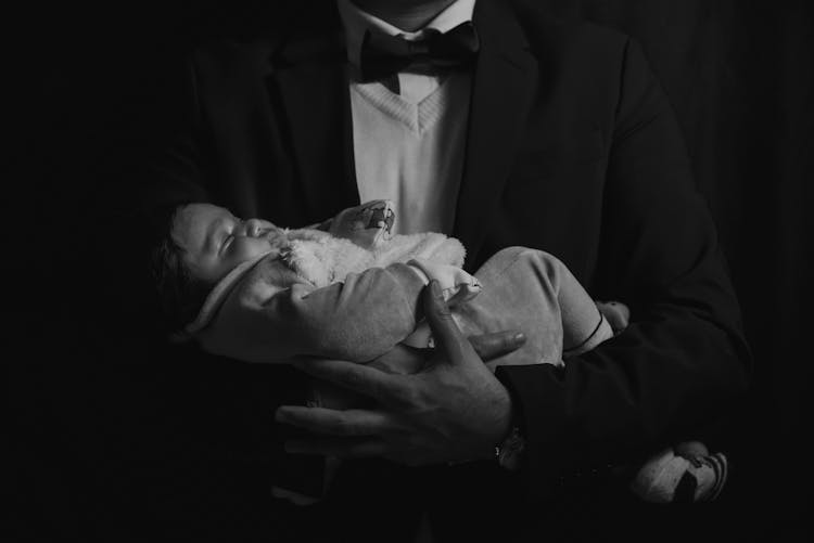 Man In A Suit Holding A Sleeping Baby