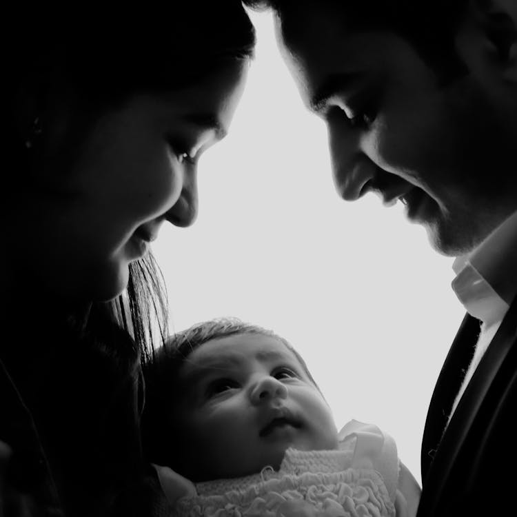 Black And White Photo Of A Couple Looking At A Baby