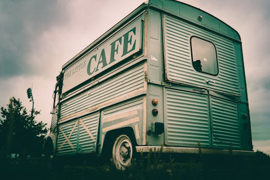 Retro-style café food truck parked outdoors under a cloudy sky, showcasing nostalgic charm.
