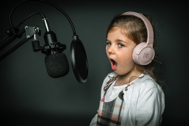 A Girl In Front Of A Microphone Waring A Headphone