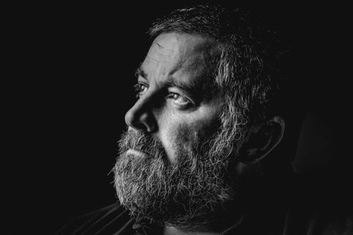 Free Intense side profile portrait of a bearded man in monochrome lighting. Stock Photo