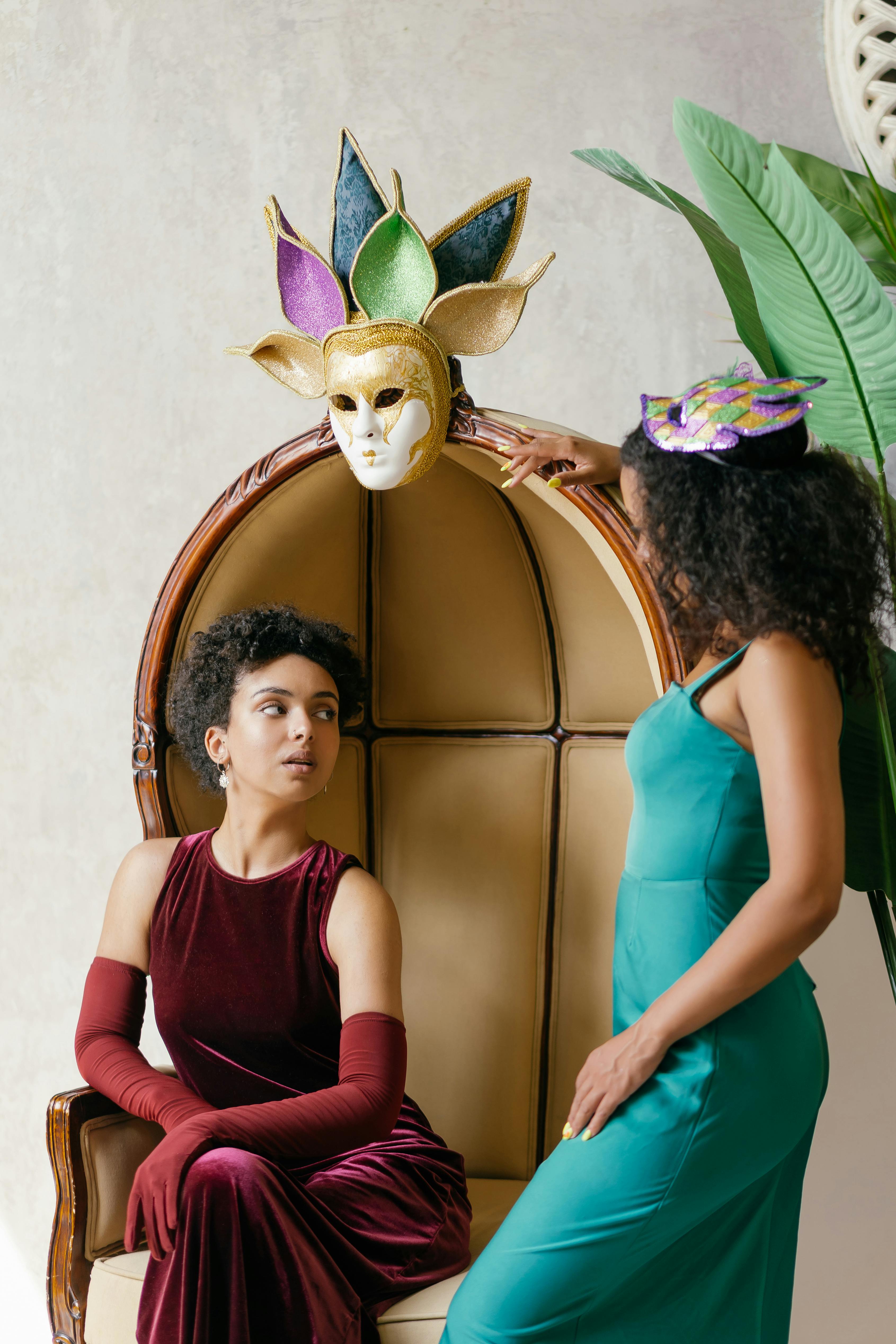 Free Stylish women in a masquerade setting with colorful masks and elegant attire. Stock Photo
