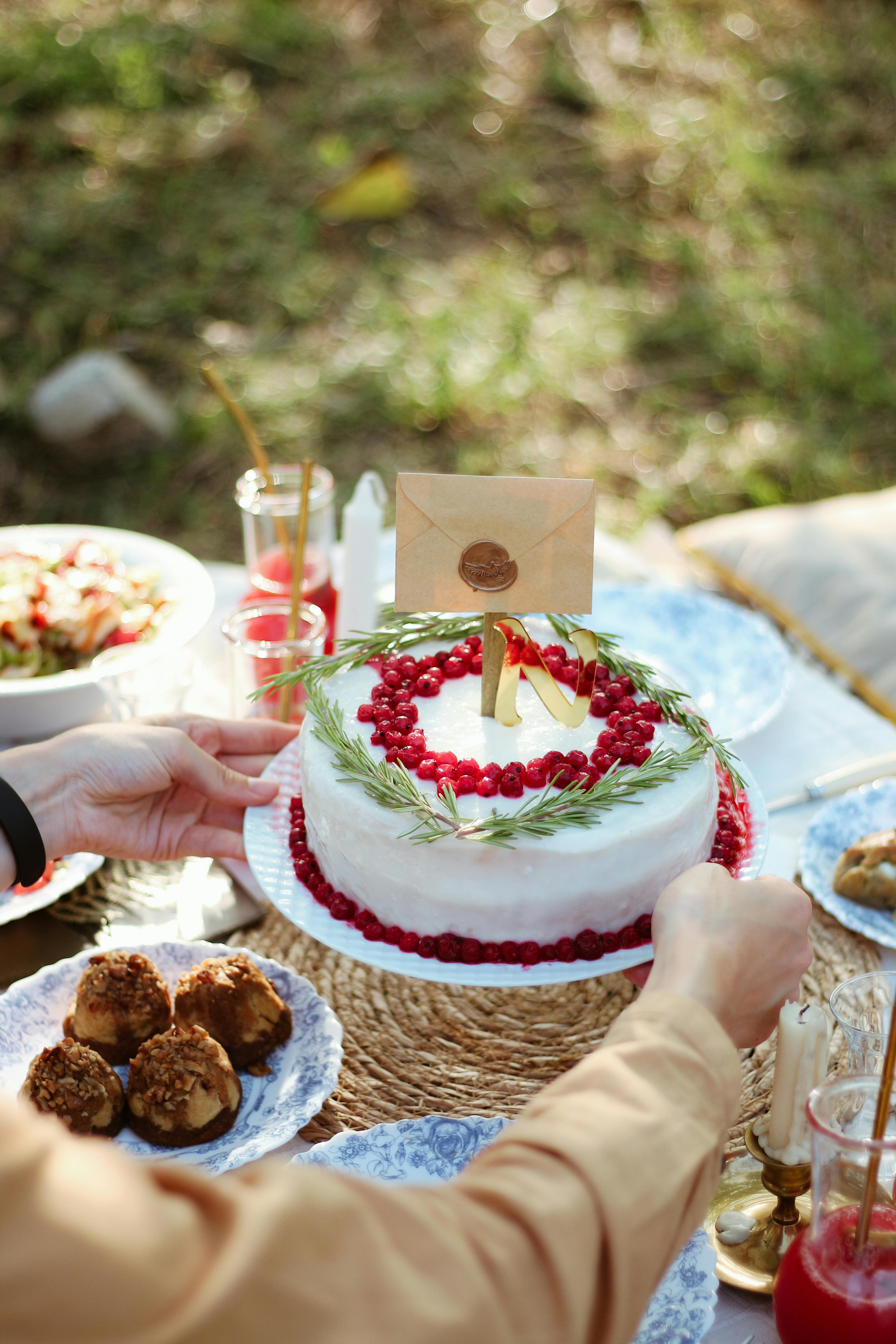 Outdoor celebration with a decorated cake, cranberries, and festive table setup.