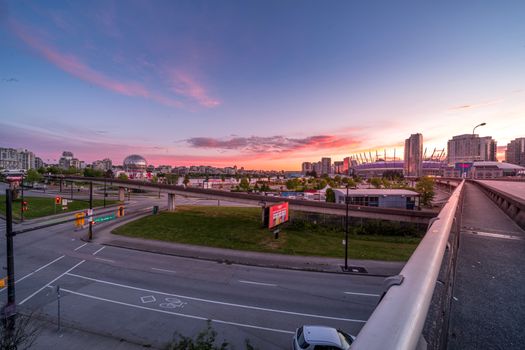 A stunning view of a city skyline with vibrant sunset colors, showcasing urban architecture and roads.