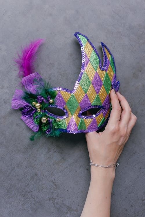 Person Holding Green Blue and Purple Floral Mask