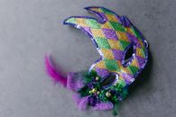 Closeup of a colorful Mardi Gras mask with vibrant purple, green, and gold decorations