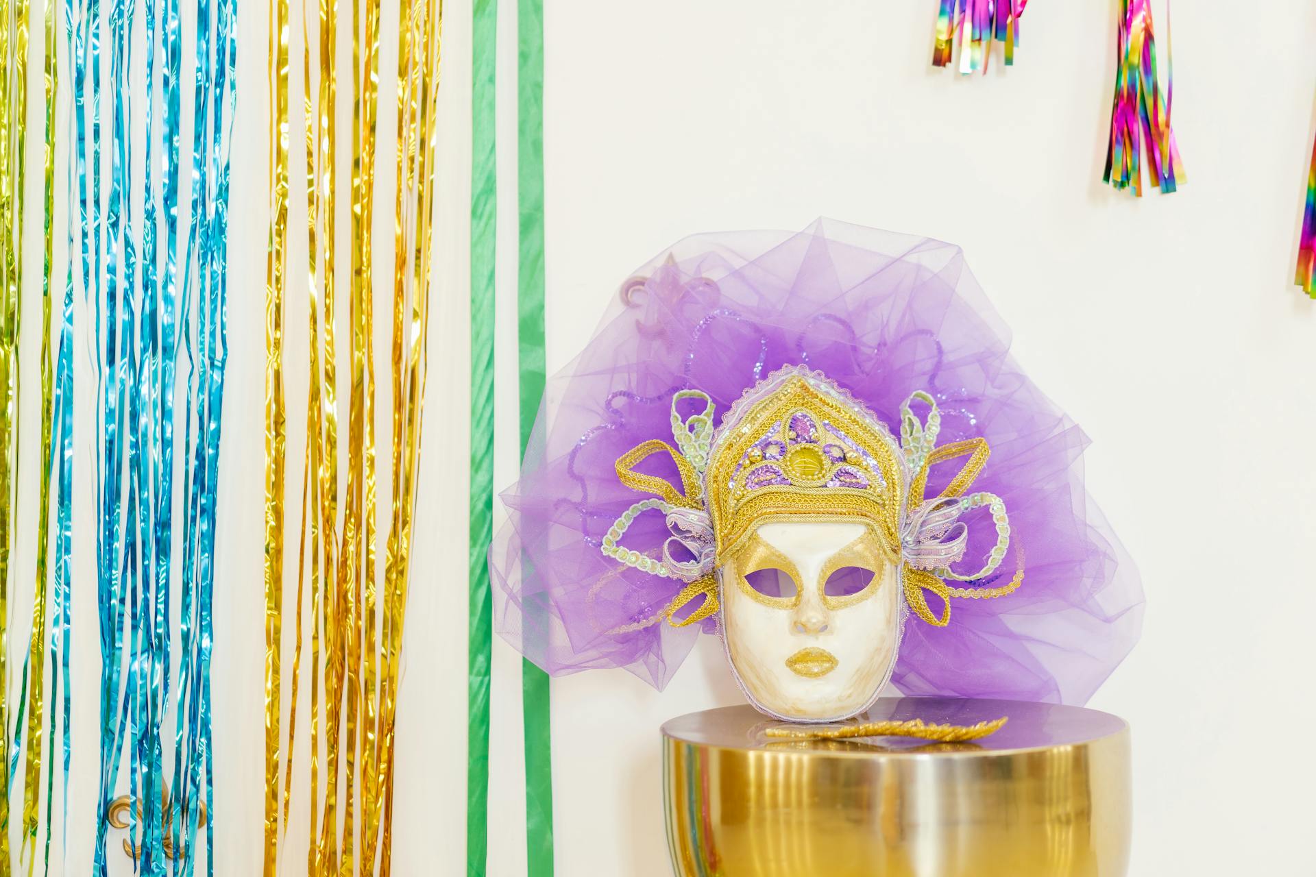 Colorful carnival mask with decorative streamers creates a festive atmosphere indoors.