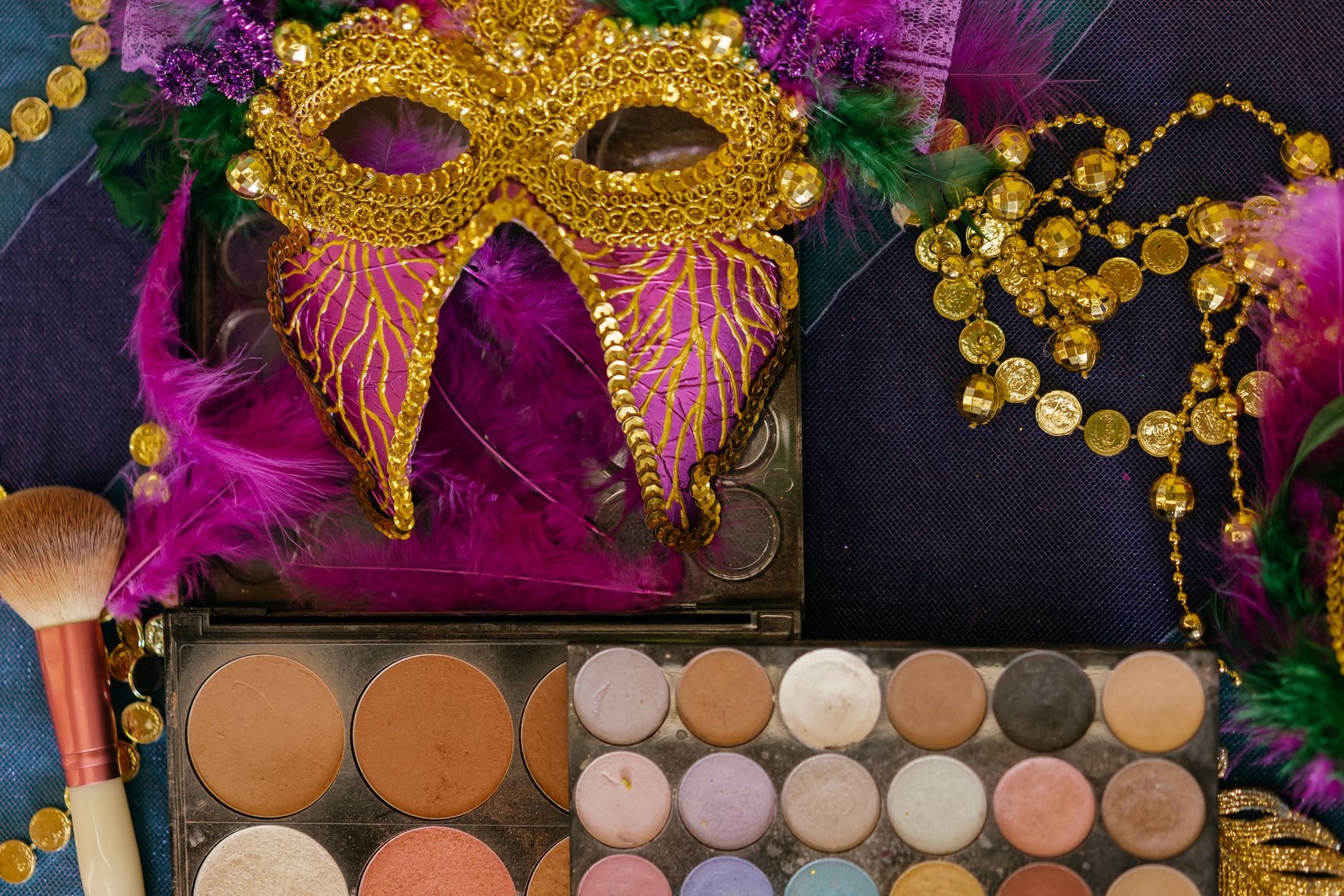 Vibrant carnival mask with makeup palette and gold beads, perfect for festive celebration themes.