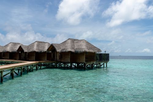 Free Overwater bungalows with thatched roofs on a turquoise ocean, under a clear blue sky in the Maldives. Stock Photo
