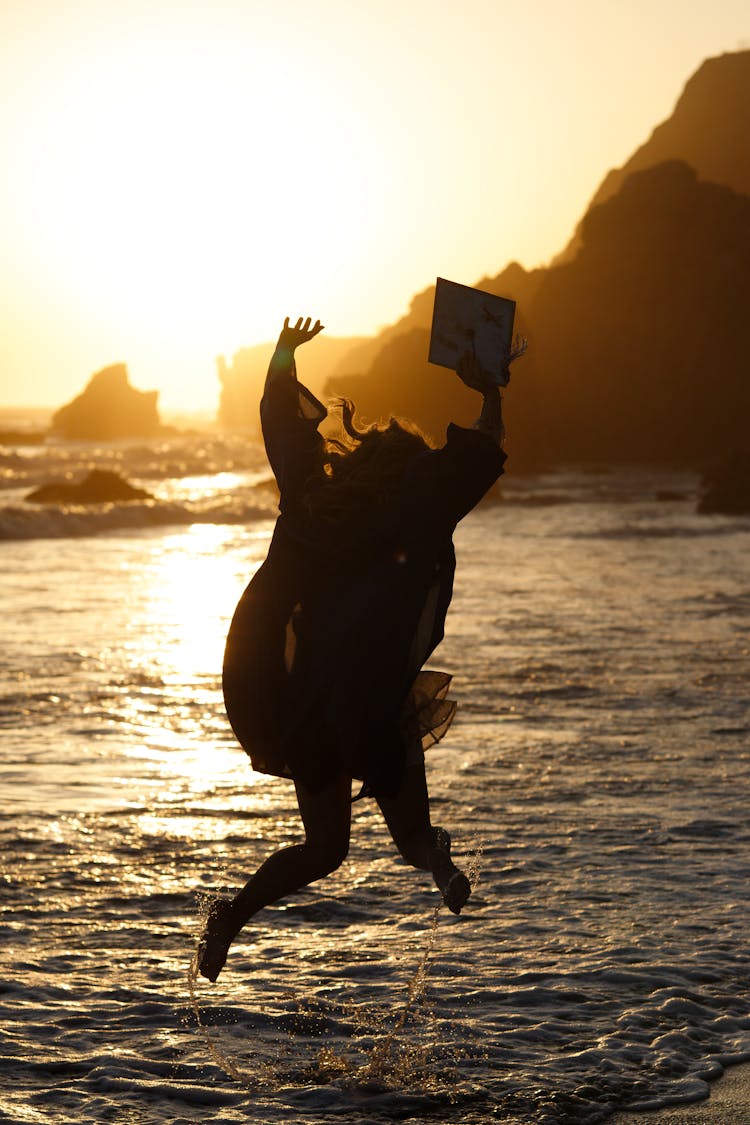 Silhouette Of A Person Jumping On Shore