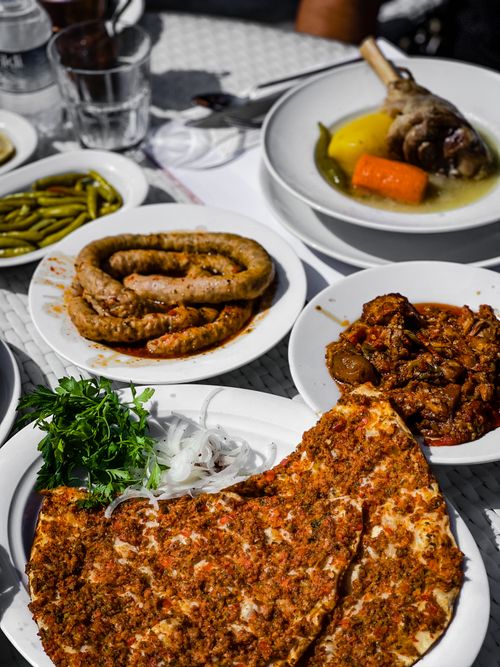 Free Assorted Mediterranean dishes including lahmacun, sausage, and stew, perfect for food photography. Stock Photo