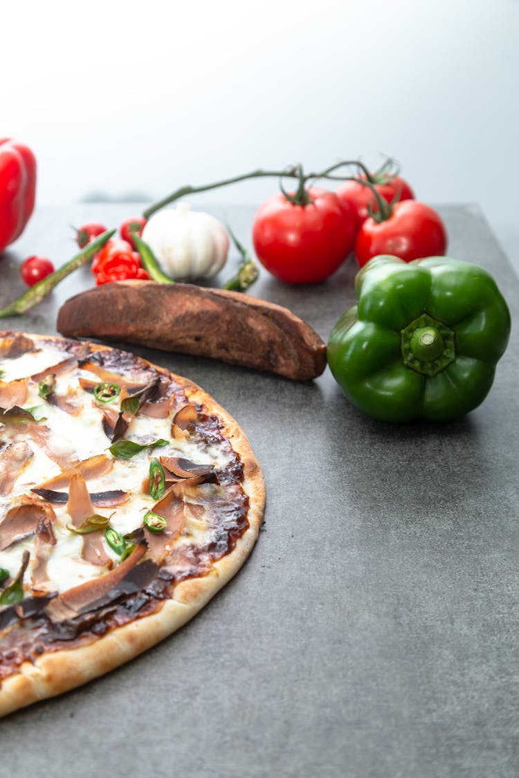 Green Bell Pepper And Tomatoes Near A Pizza