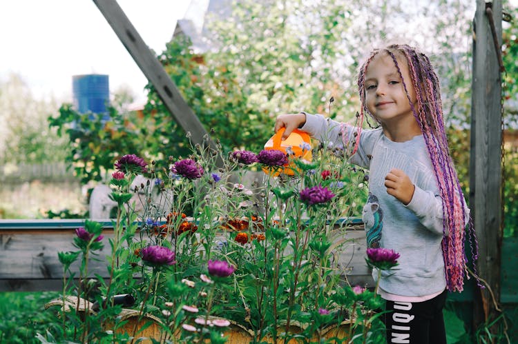 Girl With Braided Hair Watering A Plant