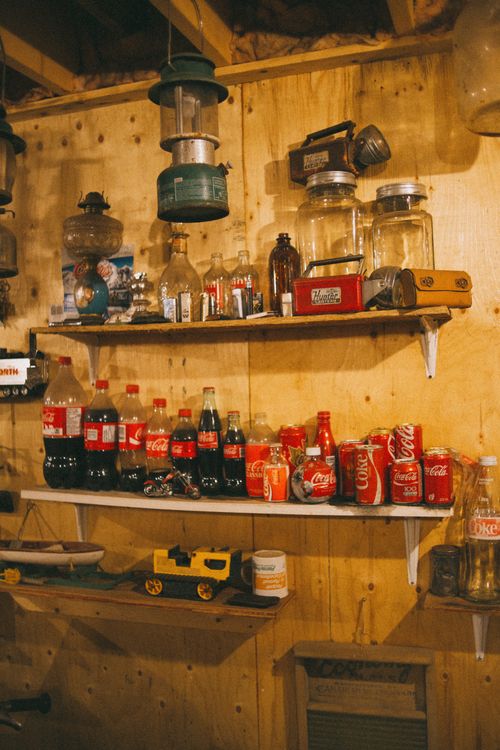 Free A rustic display of vintage soda bottles on wooden shelves with nostalgic items. Stock Photo