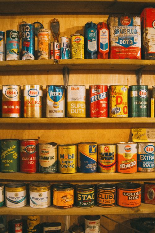 Free A collection of vintage oil and tin cans displayed on rustic wooden shelves, showcasing a retro aesthetic. Stock Photo
