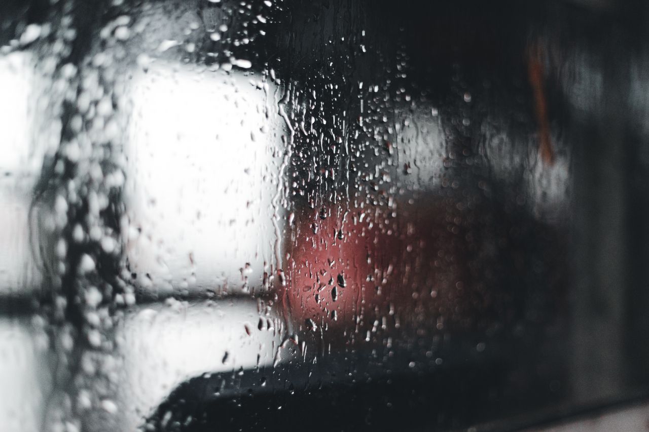 close up of raindrops on a window with a blurred background capturing