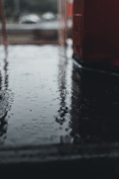 Artistic close-up of a wet surface with raindrops, capturing a moody and rainy atmosphere outdoors.