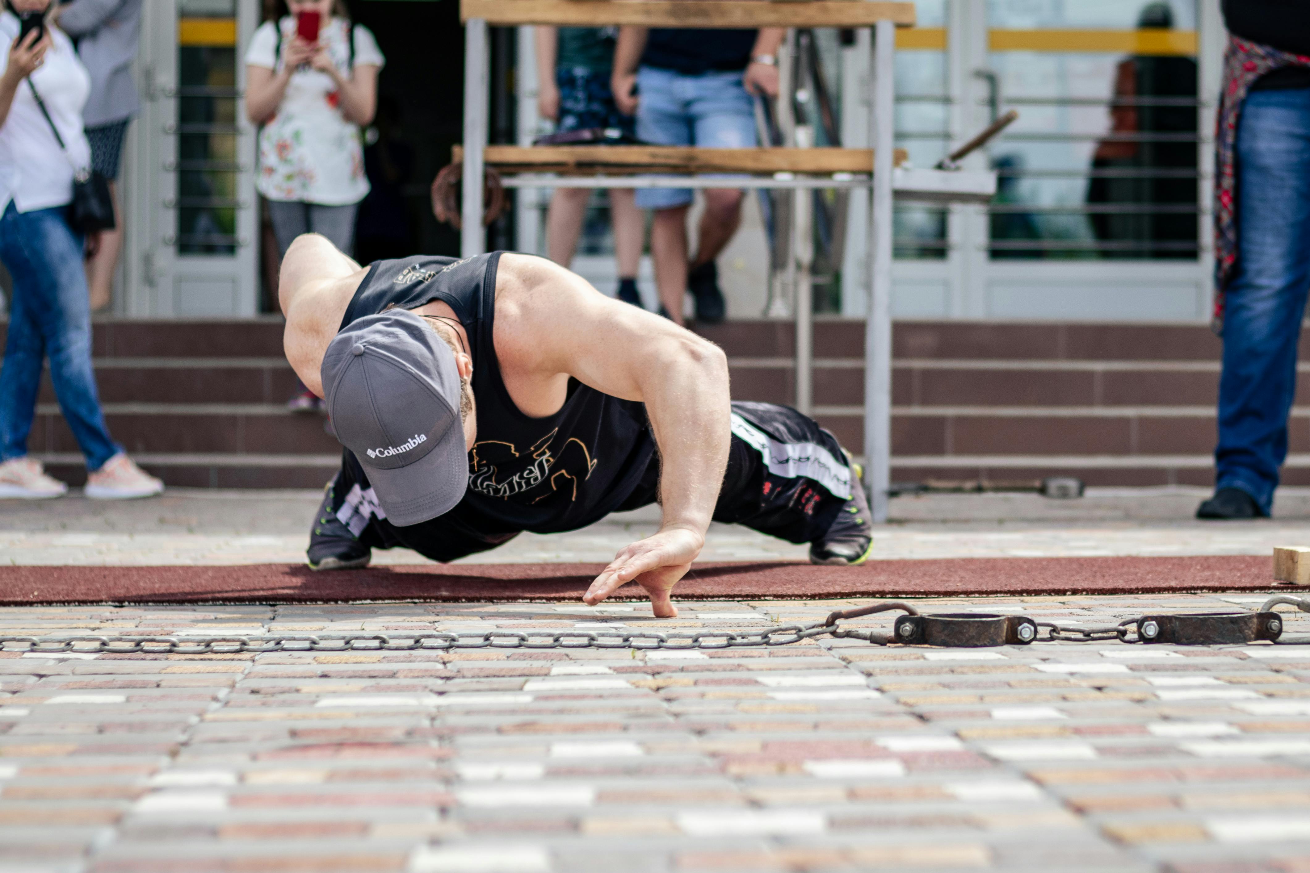 A strong man executes a one-arm push-up on the street, showcasing strength and endurance.